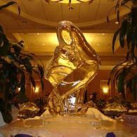 Gold ice sculpture in a warmly lit hotel lobby, surrounded by plants and chandeliers