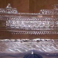 Ornate clear decorative ice sculpture of a cruise ship on water as a centerpiece with a dark background