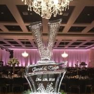 Wedding reception display with illuminated initials and names under a chandelier in a purple-lit ballroom