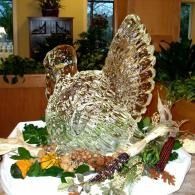 Ice sculptured turkey centerpiece on a platter with greenery and fruit decorations