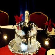 Chrome ice bucket with a bottle, surrounded by candles and red flower decorations on a table
