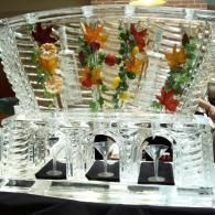 Colorful gummy candies arranged in clear tiered ice sculpted display containers on a reflective table.
