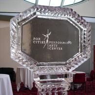 Clear glass award with Fox Cities Performing Arts Center logo on a table in a banquet hall