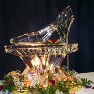 Glass high-heeled shoe sculpture on a jeweled pedestal with flowers and lights