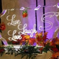 Decorative “Live Laugh Love” sign with flowers and purple lighting at an event backdrop