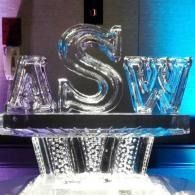 Glass ASW letters on a lit display stand with blue and purple lighting.