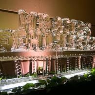 Two rows of clear ice sculpted letters on a lit shelf against a warm wall.