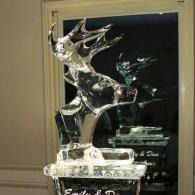 Clear glass deer sculpture on a pedestal in front of a mirrored background