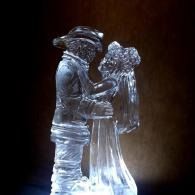 Translucent ice sculpture of a couple embracing, lit against a dark background