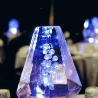 Blue crystal-like decorative centerpiece with glowing lights on a dark table setting