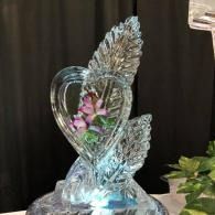 Clear glass swan figurine with pink flowers inside and wing-like details on a dark background