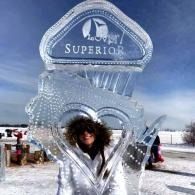 Person posing inside an ice sculpture with a heart-shaped opening and 