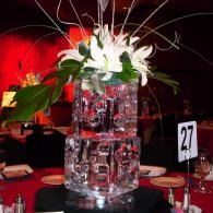 Tall floral centerpiece with white lilies in a red-lit banquet setting, table number 27 visible.
