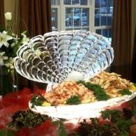 Buffet table with a decorative clam-style fan display and food platters in a dining room
