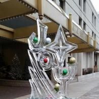 Abstract metal sculpture with colorful spheres and sculpted ice spelling JOY outside a building entrance