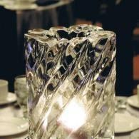 Crystal-patterned glass candle holder glowing on a table with dishes in the background