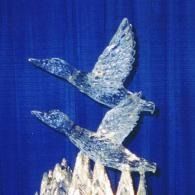 Two geese birds flying against a deep blue background above crystalline peak