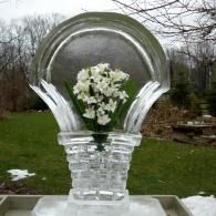 Clear glass sculpture with white flowers centered in a garden setting