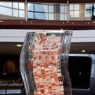 Curved red-and-white cascading art installation inside a modern atrium with windows.