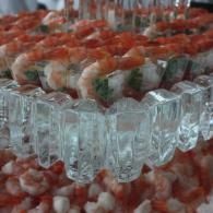 Ice sculpture centerpiece surrounded by red and white floral decorations and glass-like columns