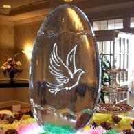 Clear ice sculpture with engraved dove, lit on a banquet table in a reception room