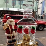 Santa figures beside a large clear holiday ice sculpted fireplace.