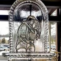 Glass sculpture of an embracing couple in a windowed indoor setting