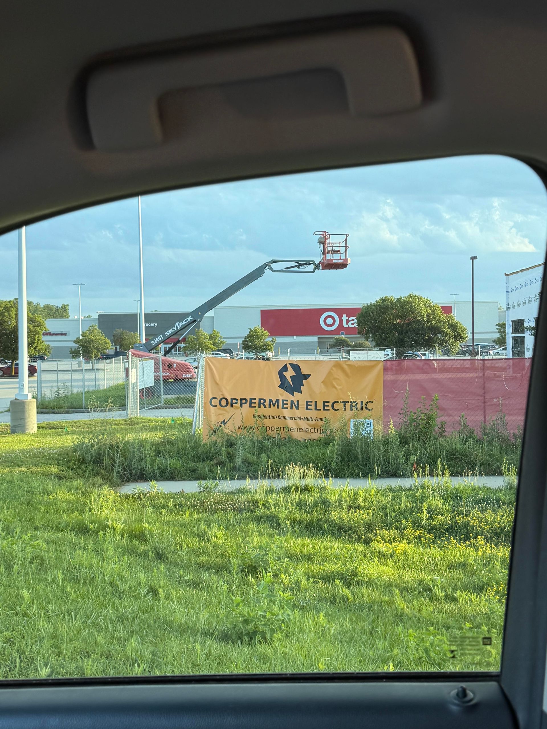 Roadside sign for Connecticut College with a crane and red building in the background.