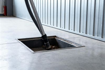 Long hose inserted into a floor cleaning pit in an industrial room.