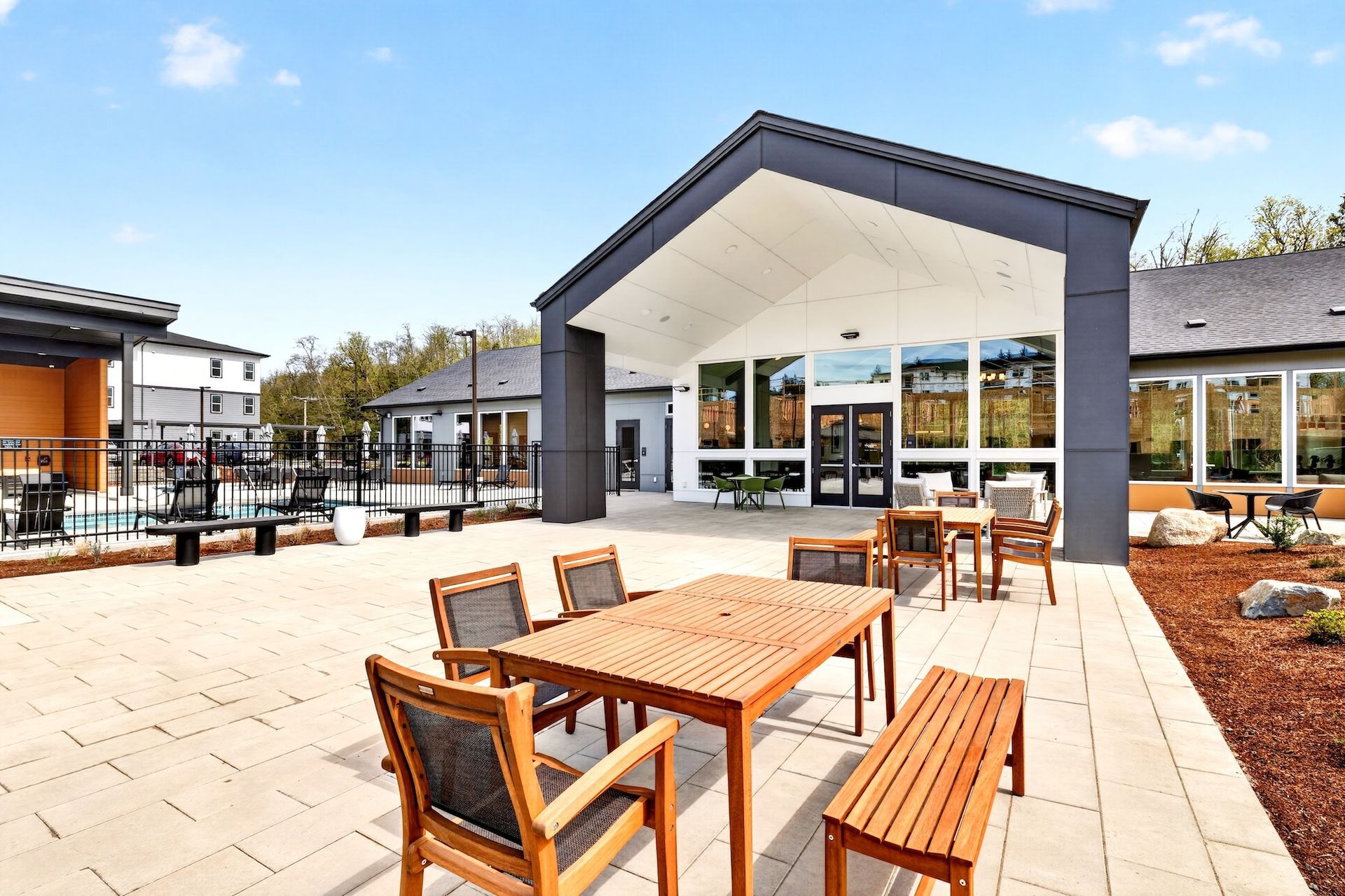 Outdoor patio with wooden tables and benches outside a modern café under a clear sky