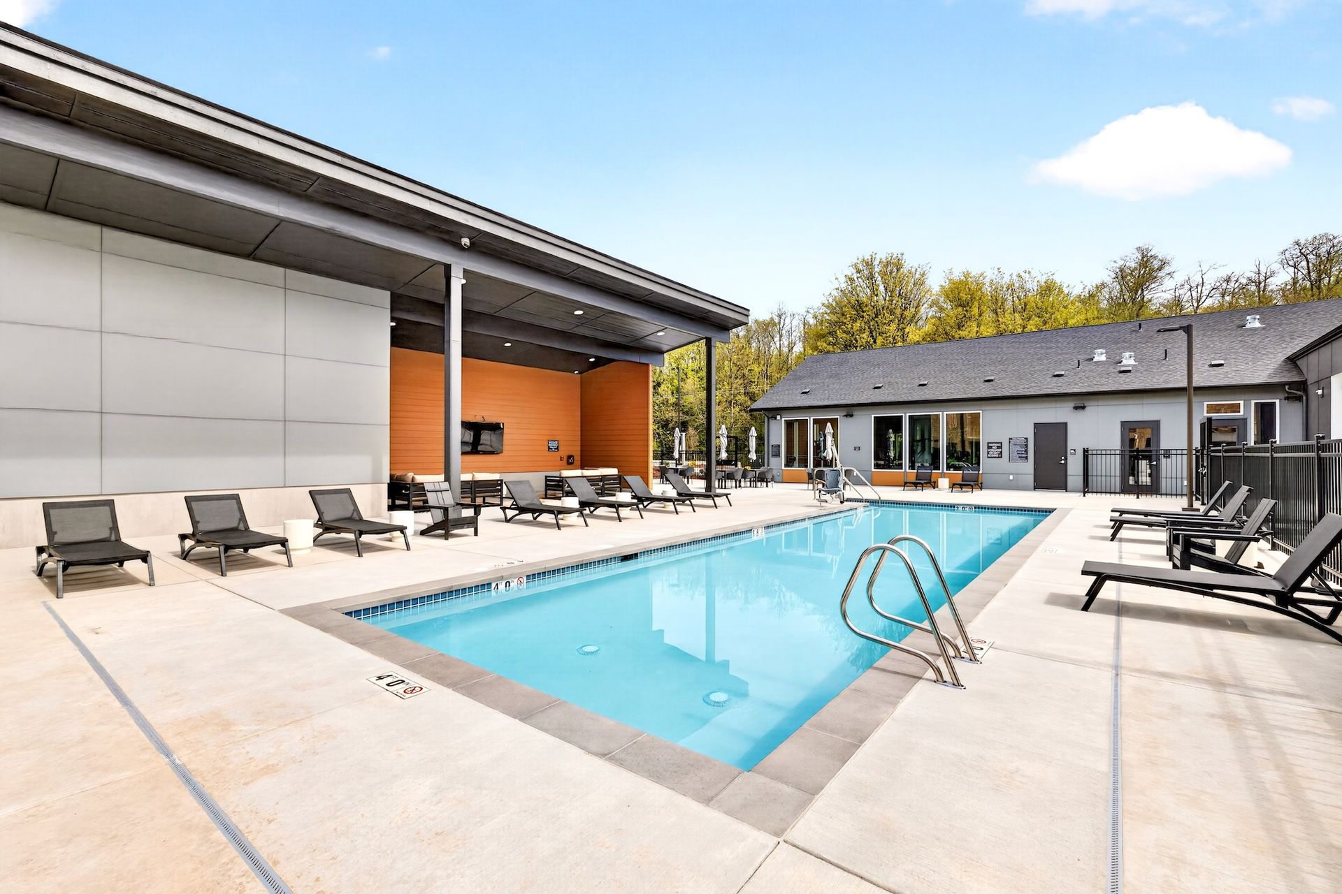 Outdoor pool courtyard with lounge chairs and modern buildings under a clear sky