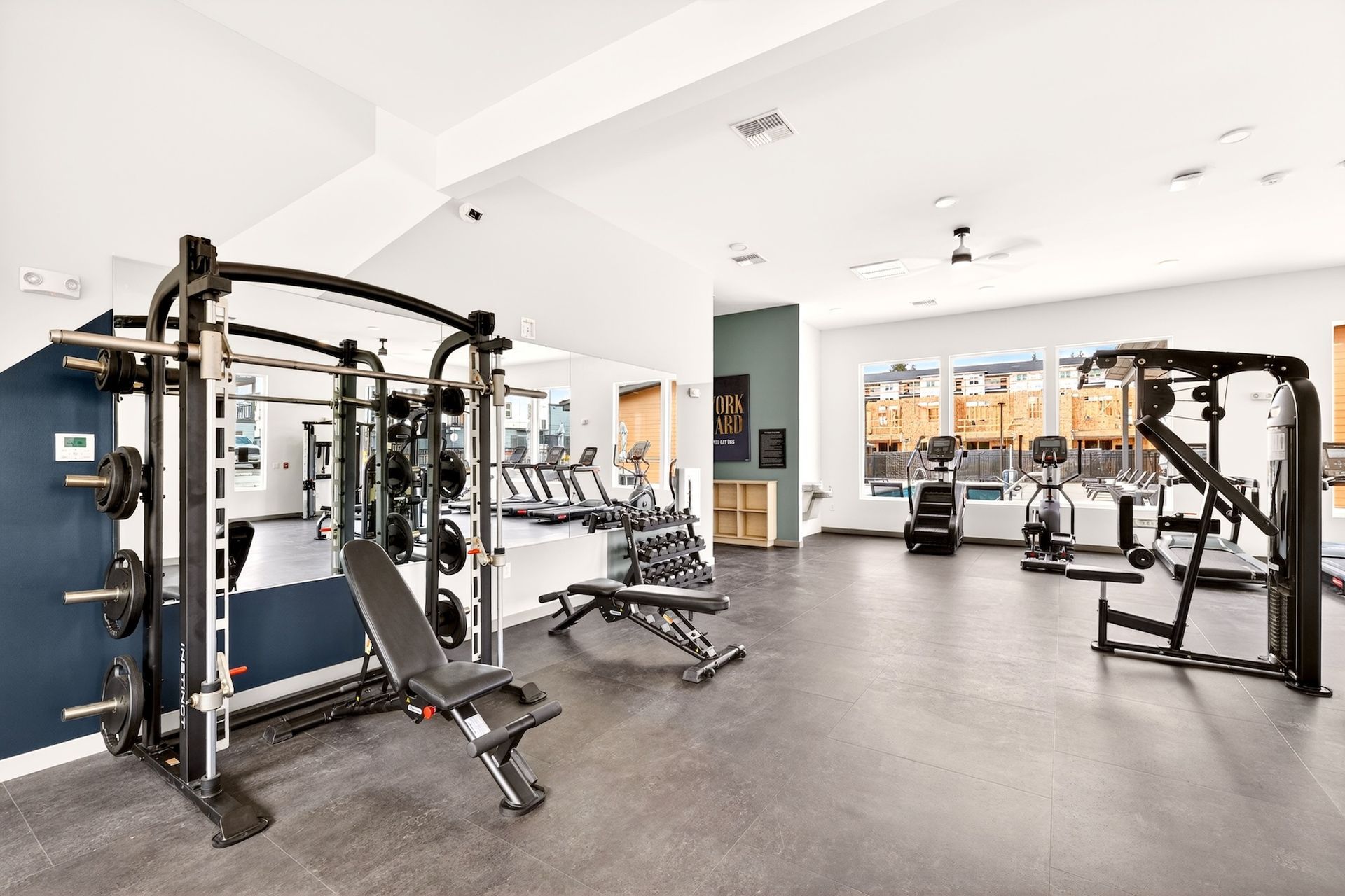 Modern gym with weight machines, benches, and mirrors on a bright white interior