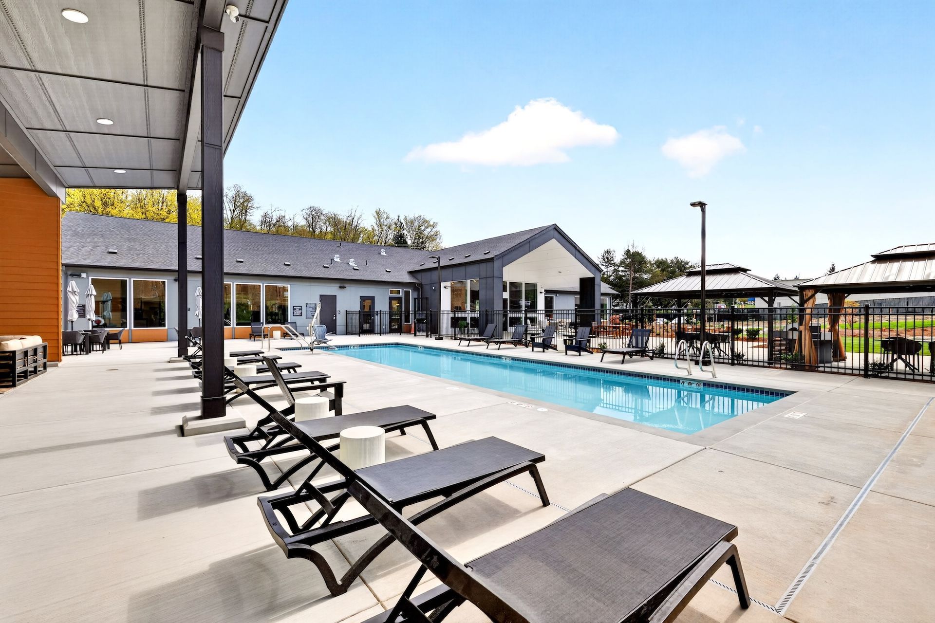 Outdoor apartment pool with lounge chairs and a covered patio area