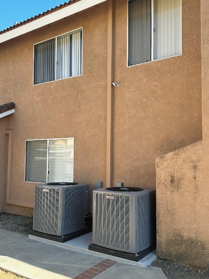 Two air conditioners are on the side of a building