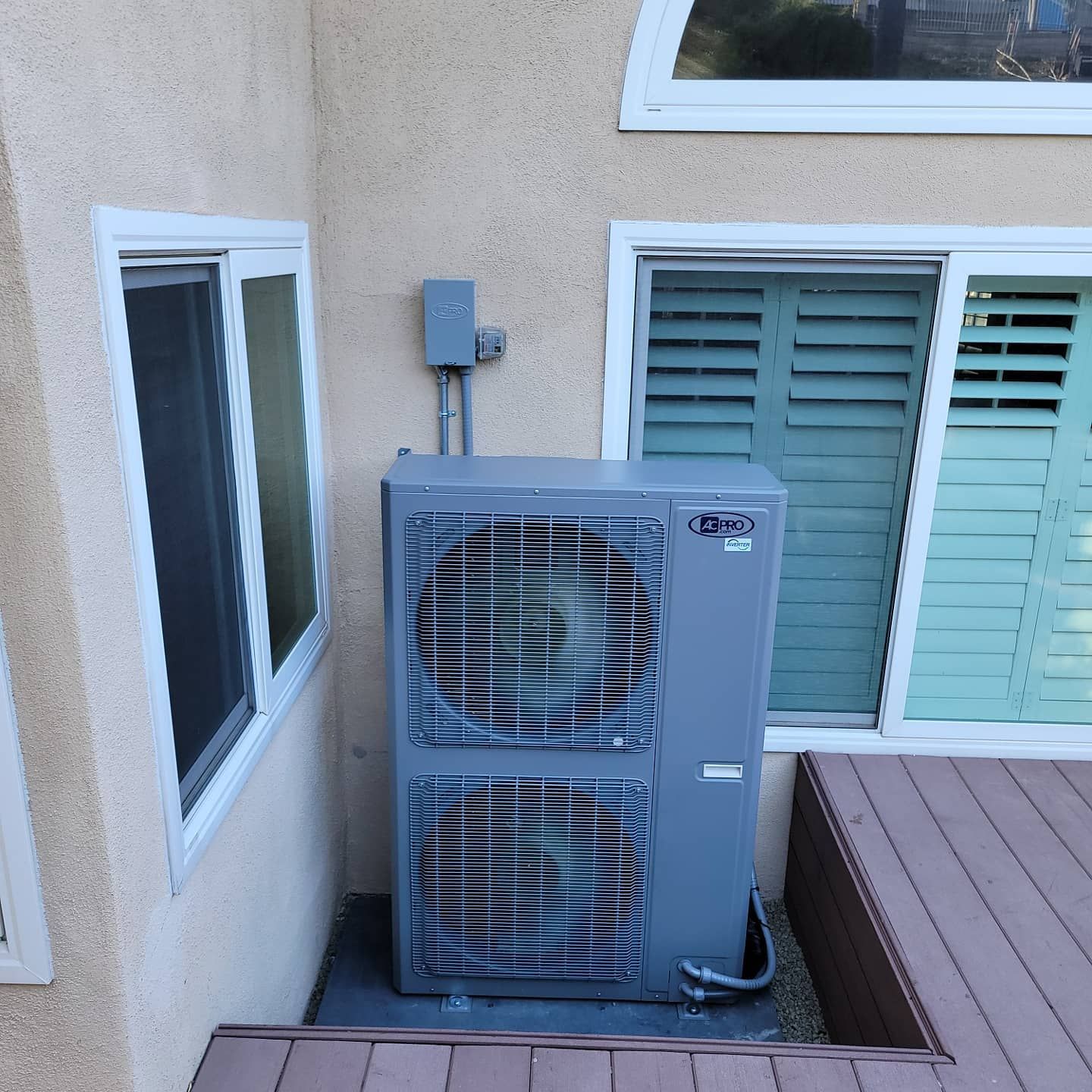 A gray air conditioner is mounted on the side of a building