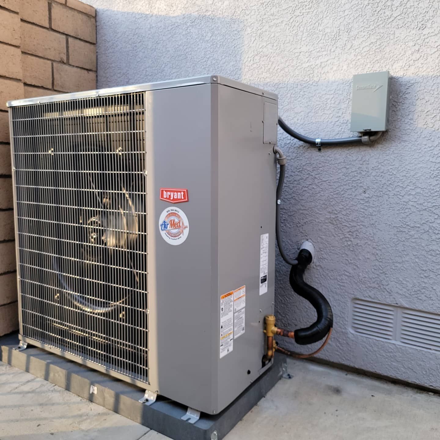 A bryant air conditioner is attached to the side of a building