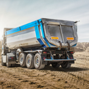 Blue and silver dump truck driving on a dirt construction site