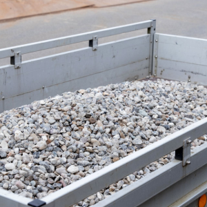 Metal trailer filled with gray gravel at a construction site