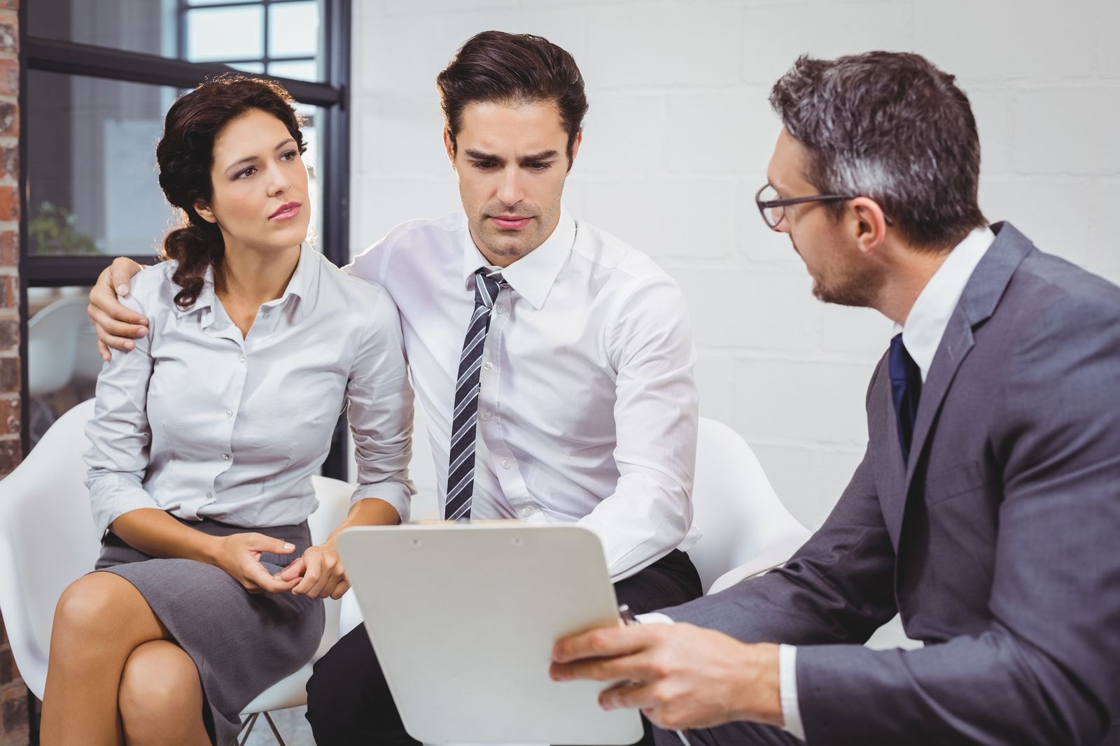 Three businesspeople in discussion, with one showing a laptop during a meeting.
