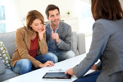 Two people discussing documents with a counselor in a bright living room