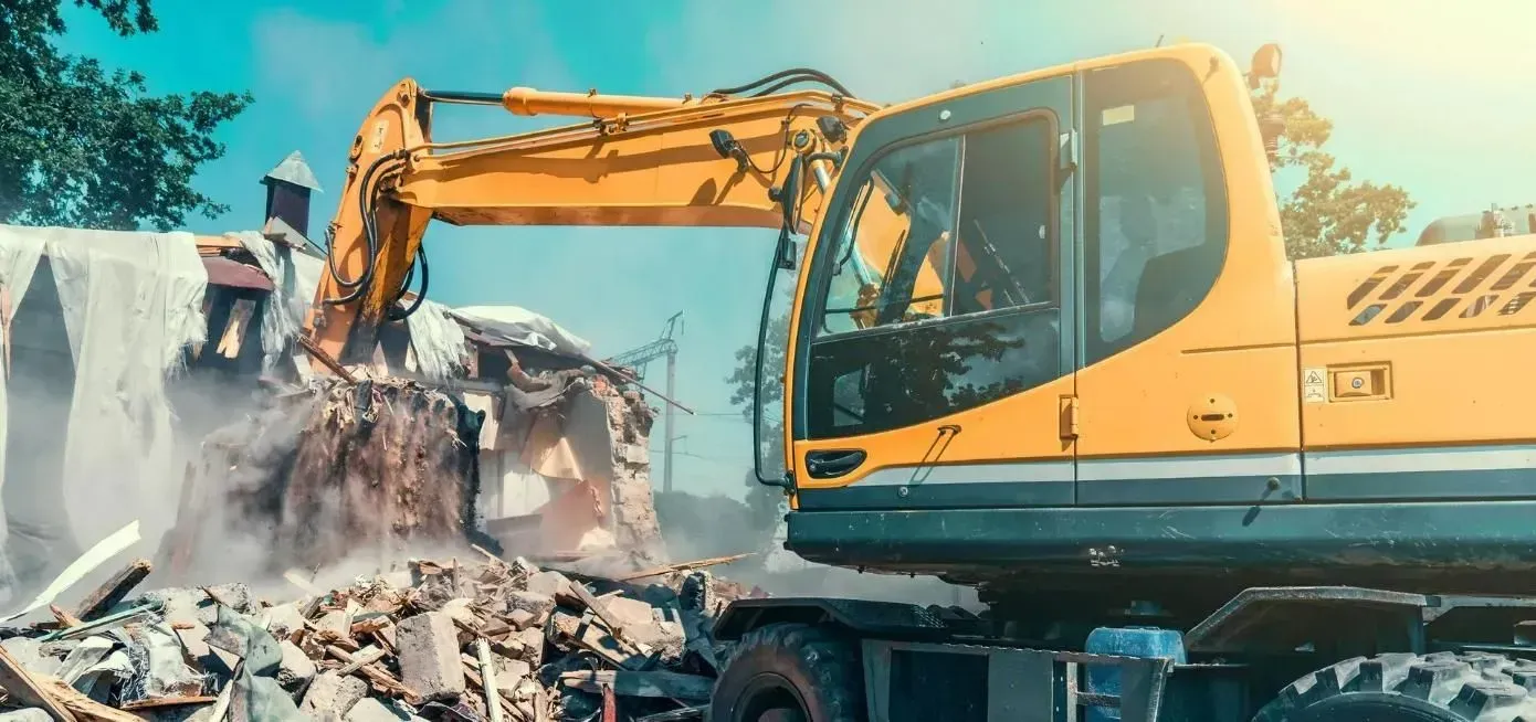 A Yellow Excavator Demolishes a Building Creating a Cloud of Dust — Boland Contracting In Wellington, NSW