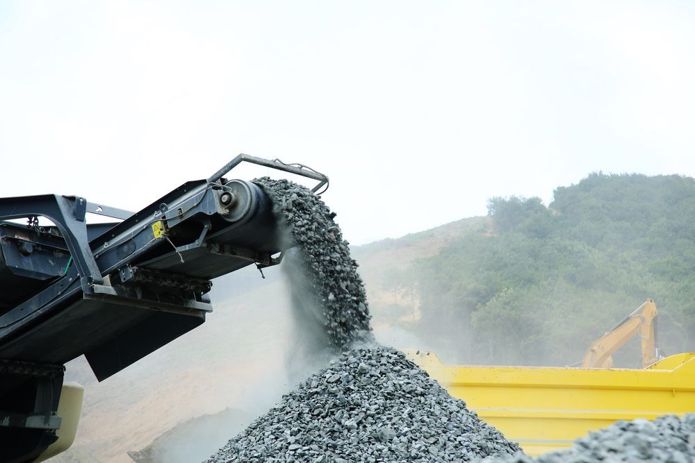 Crusher Machine Pouring Gravel Into a Yellow Dump Truck — Boland Contracting in Wellington, NSW