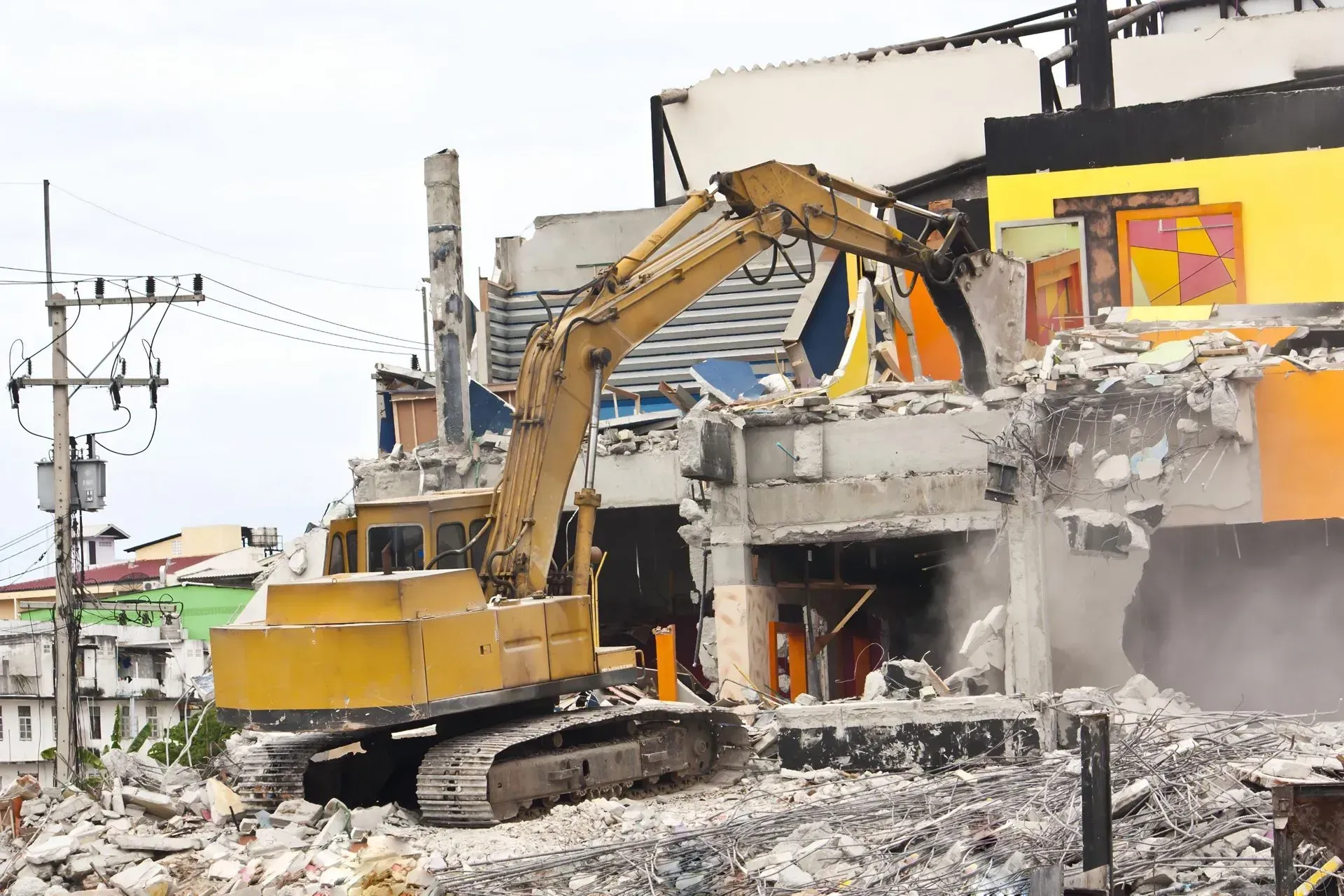 Yellow Excavator Demolishing a Building Debris Scattered — Boland Contracting In Orange, NSW
