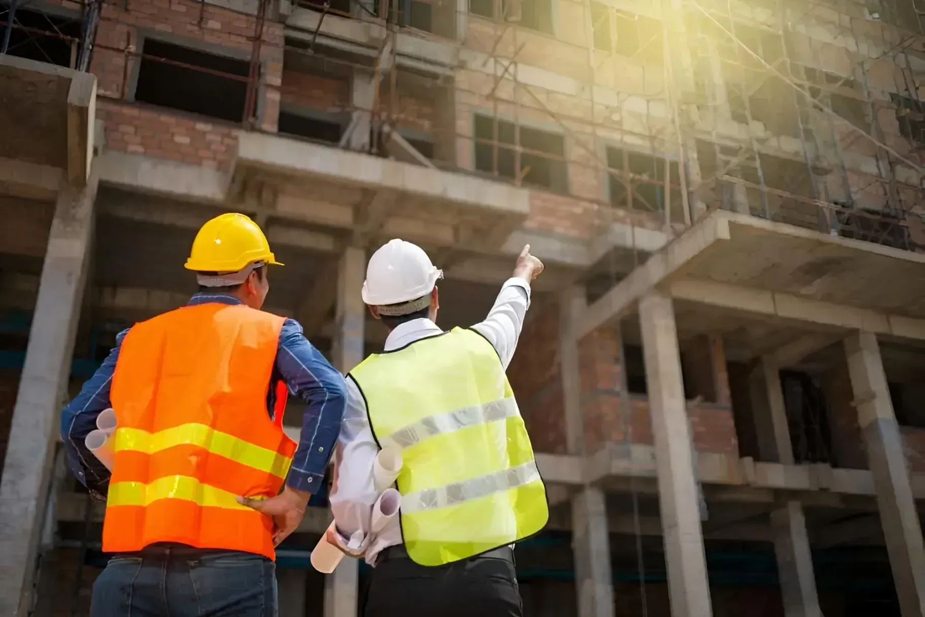 Two Construction Workers in Vests and Helmets Examining a Building Under Construction — Boland Contracting In Wellington, NSW