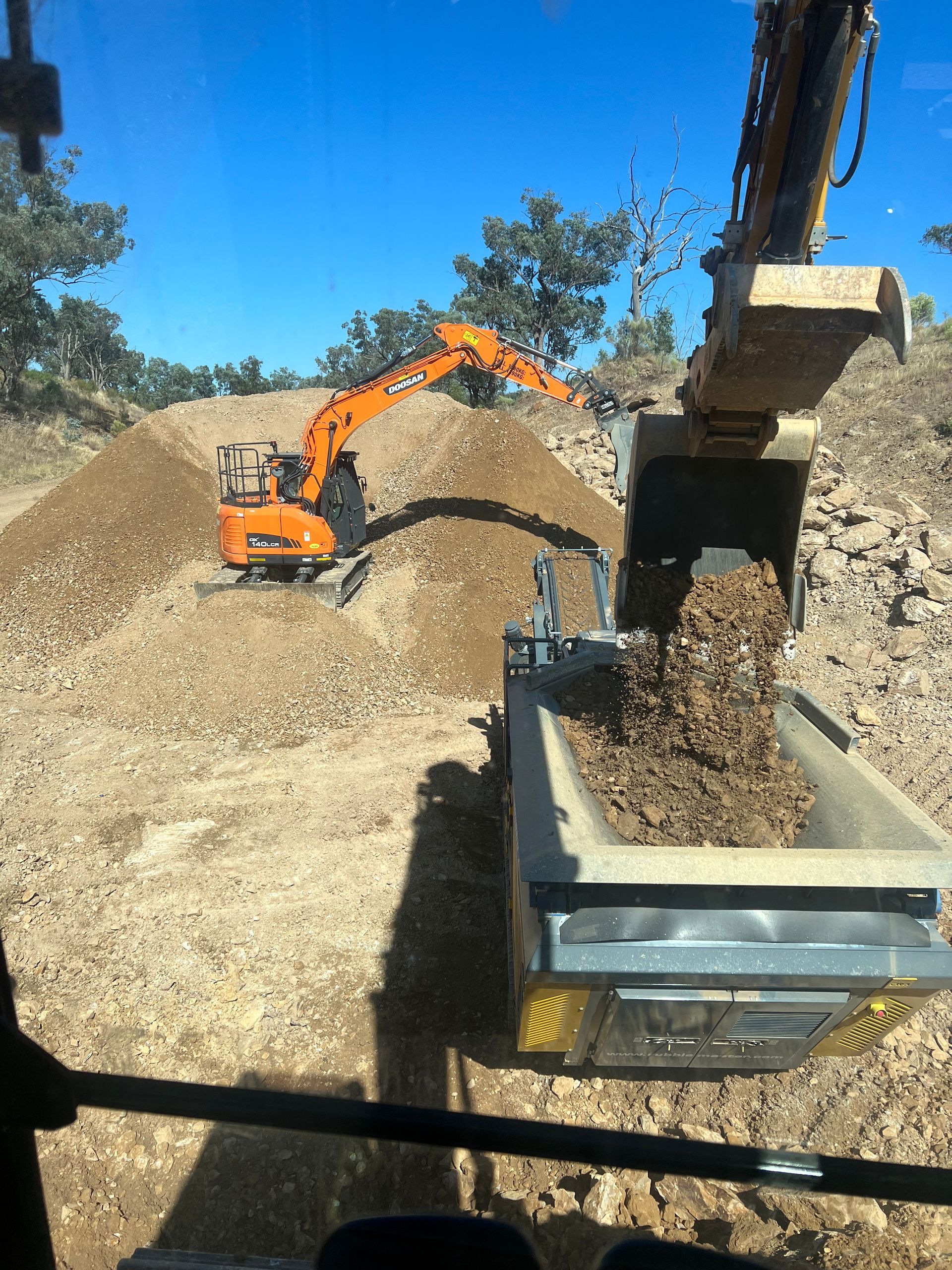Orange Excavator Loading Dirt Into a Dump Truck at a Construction Site in Dubbo