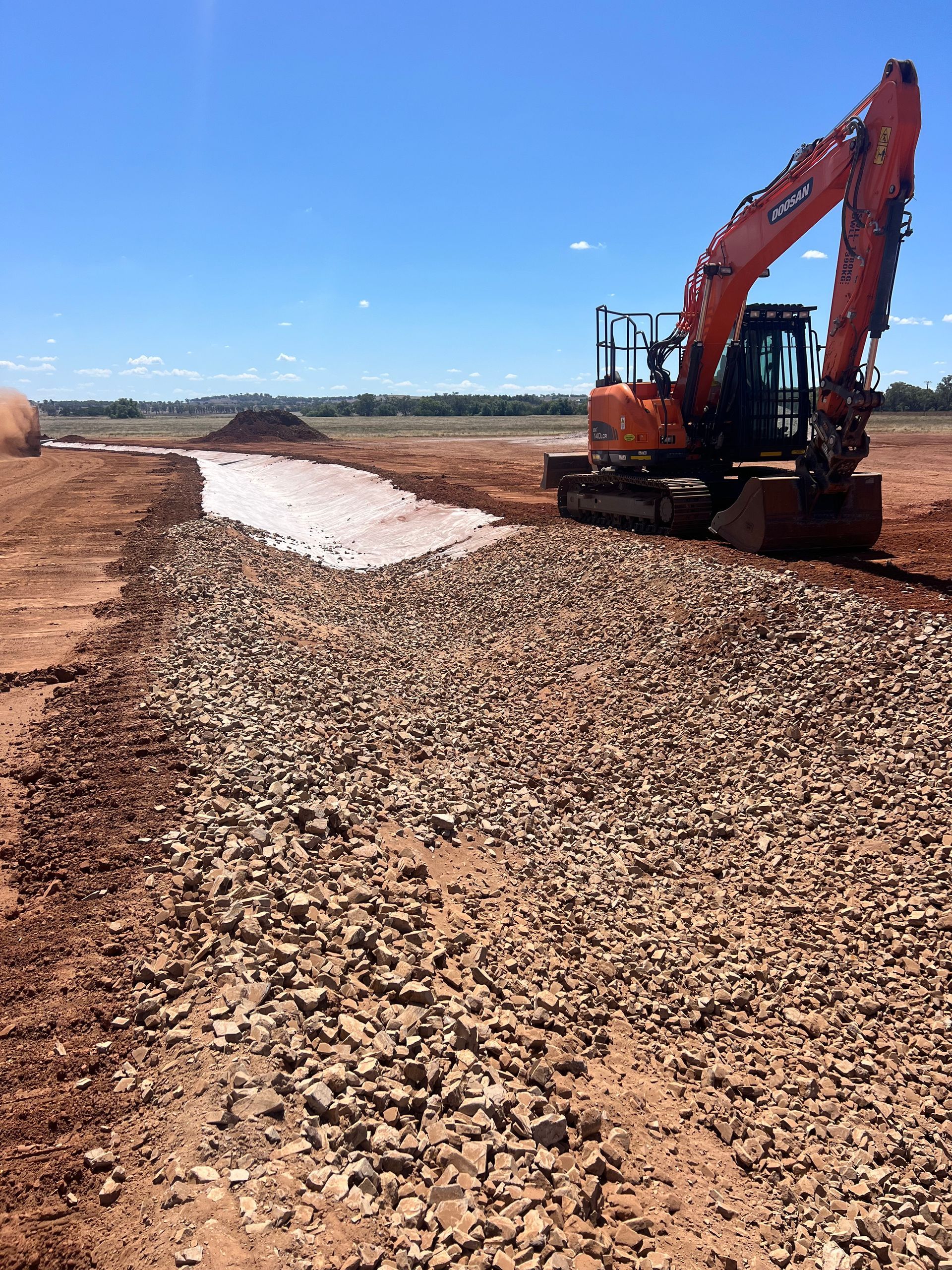 Orange Excavator Laying Gravel on a Construction Site — Boland Contracting In Wellington, NSW