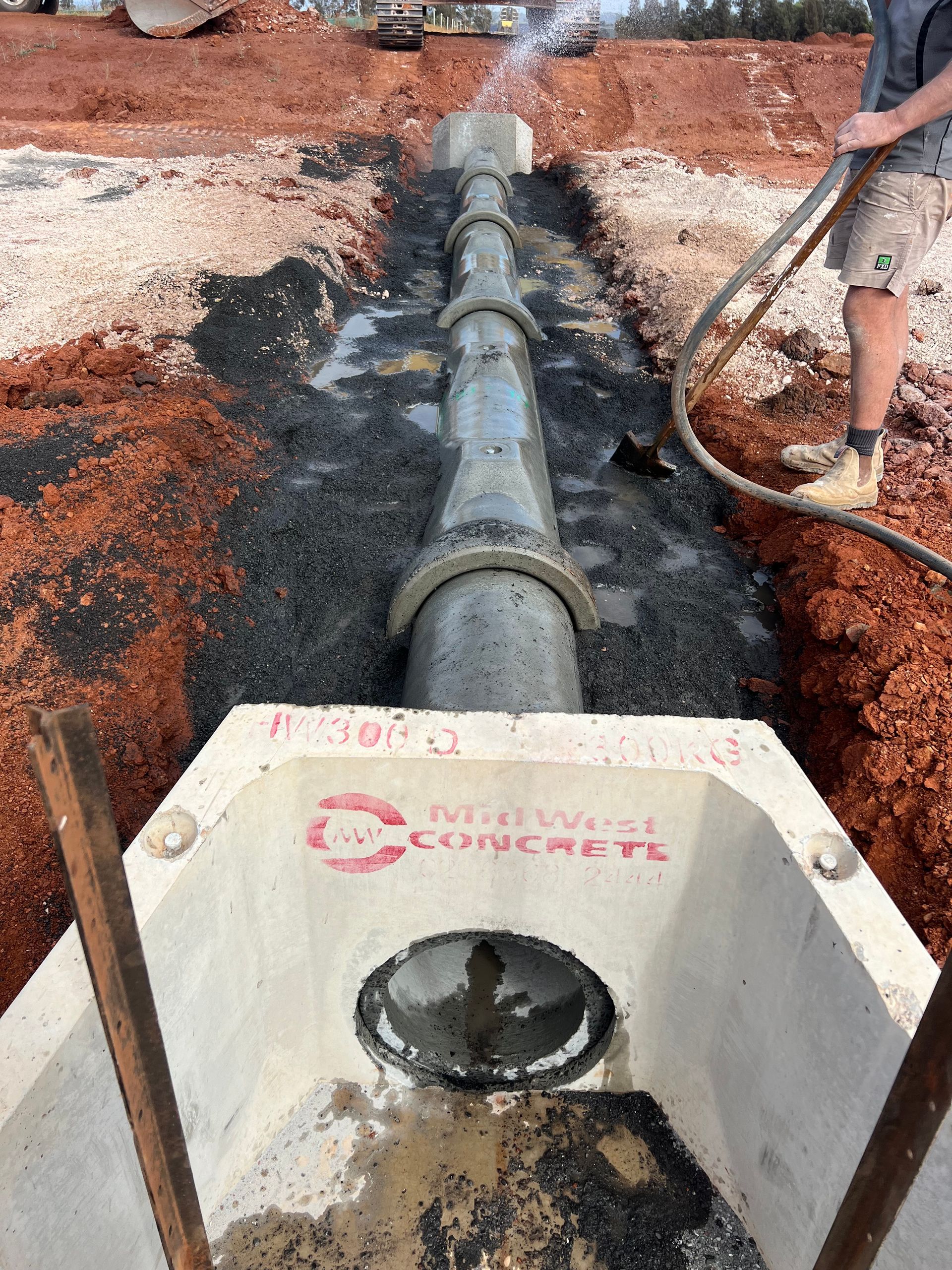 Construction Workers Installing a Concrete Pipe System in an Open Trench — Boland Contracting In Wellington, NSW