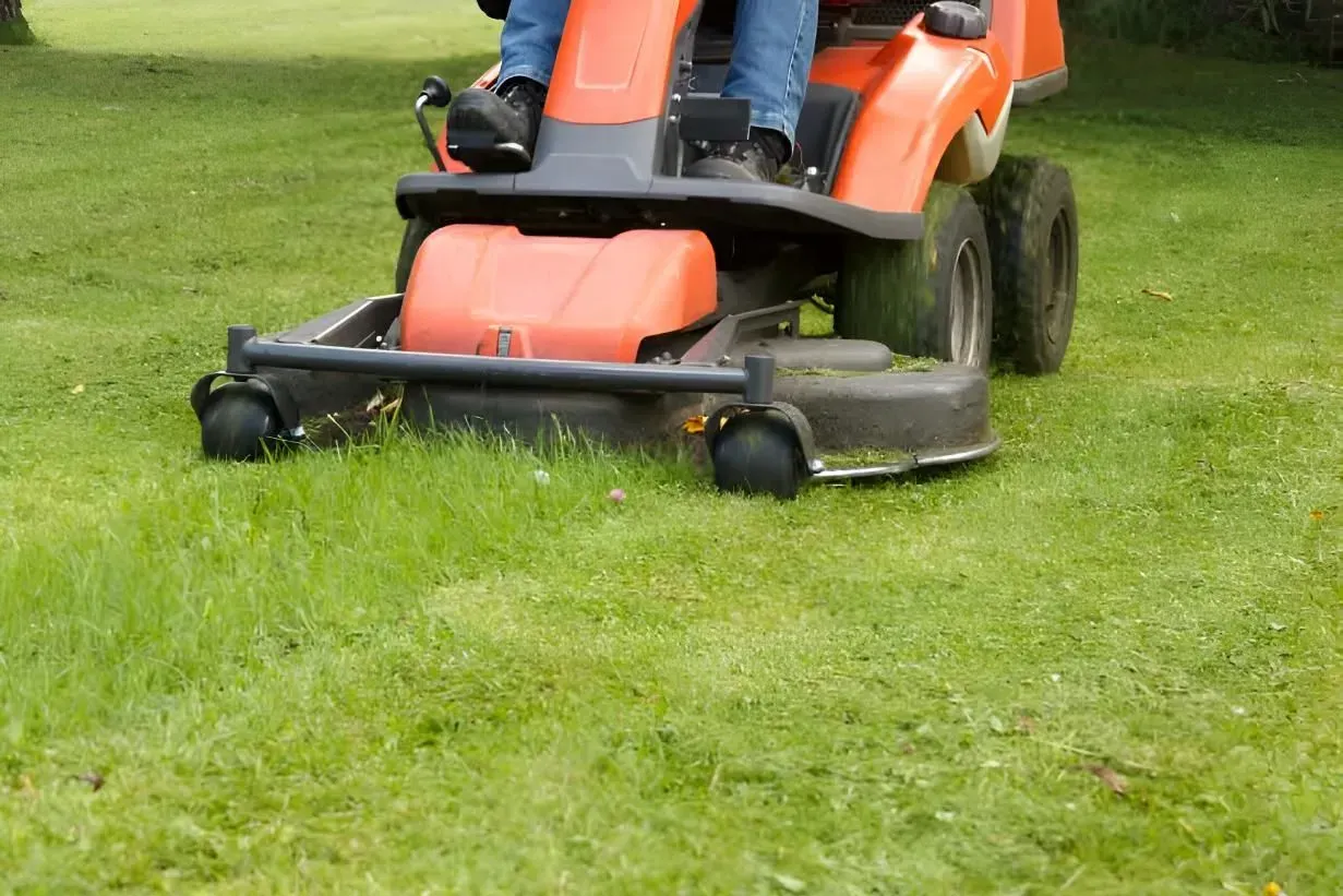 Orange Riding Lawn Mower Cutting Green Grass — Boland Contracting In Wellington, NSW