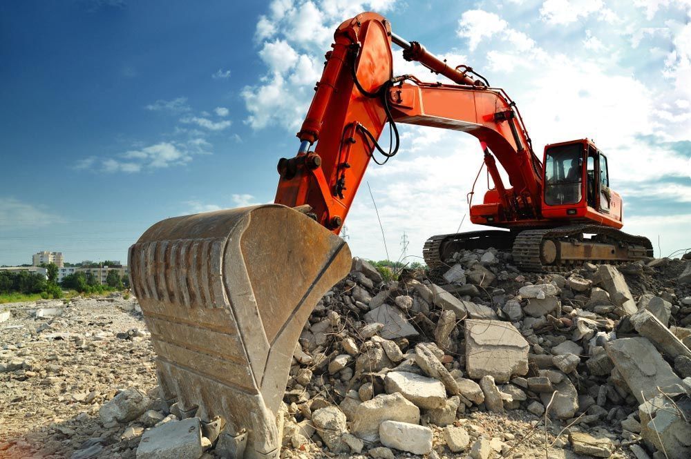 Red Excavator Scoops Debris on a Construction Site Under a Blue Sky — Boland Contracting In Wellington, NSW