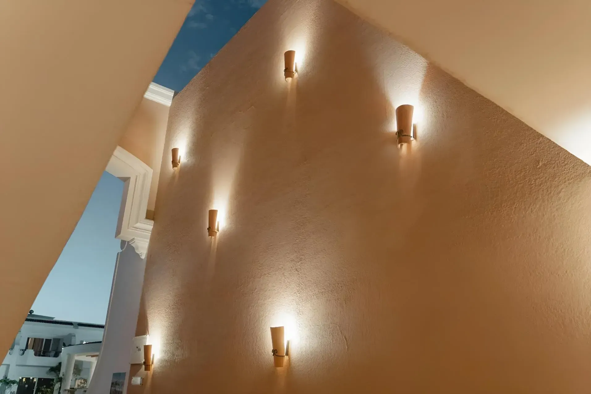 Beige Stucco Wall With Cylindrical Wall Sconces Casting Soft Warm Light — Boland Contracting In Wellington, NSW